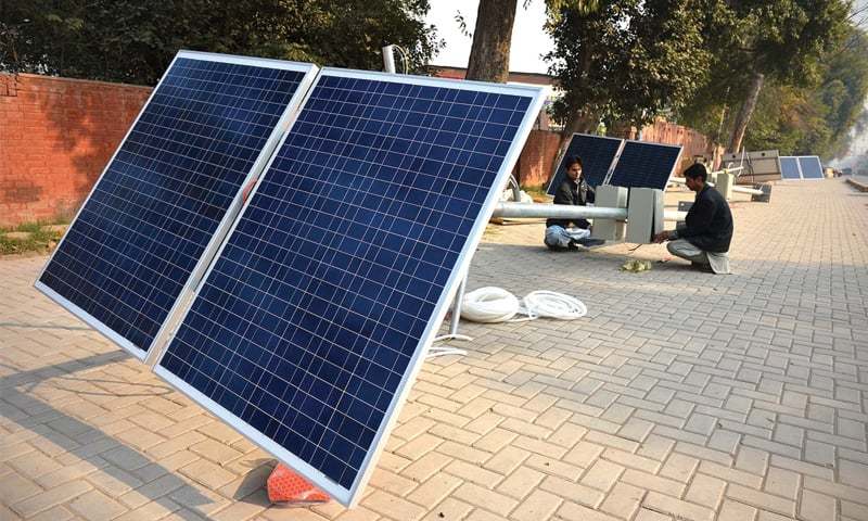 A row of solar-powered streetlights lit up at dusk along a major road in Islamabad, showcasing over 60 % solar coverage